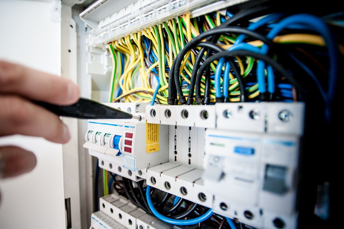 An electrician landing branch-circuit wiring inside a commercial distribution panel