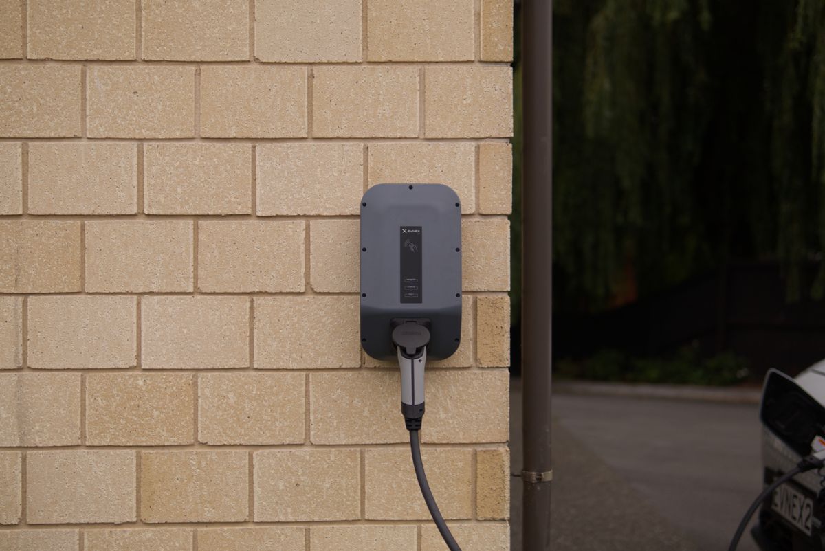 A wall-mounted Level 2 EV charging station installed on a home exterior