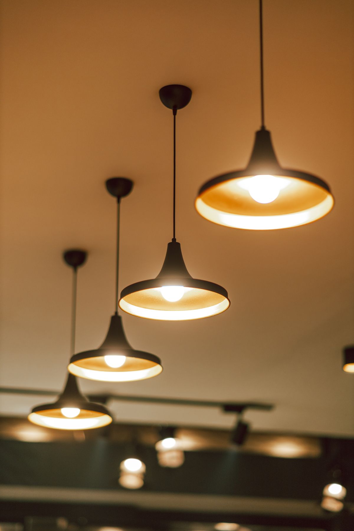 A row of warmly illuminated pendant light fixtures wired and installed