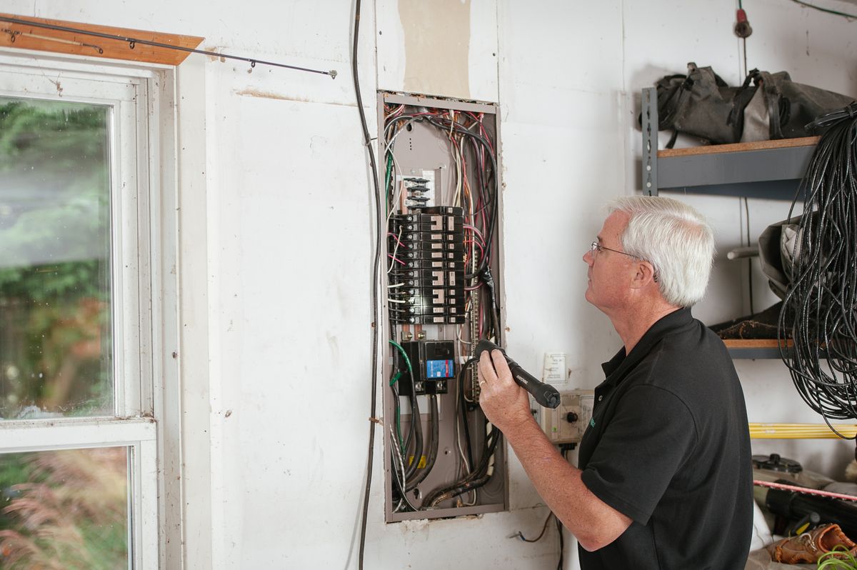 A licensed electrician inspecting a residential electrical panel and breakers