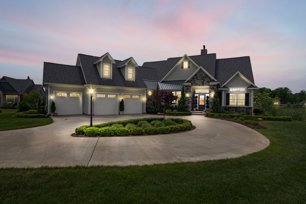A residential exterior lit at dusk by installed landscape and accent lighting